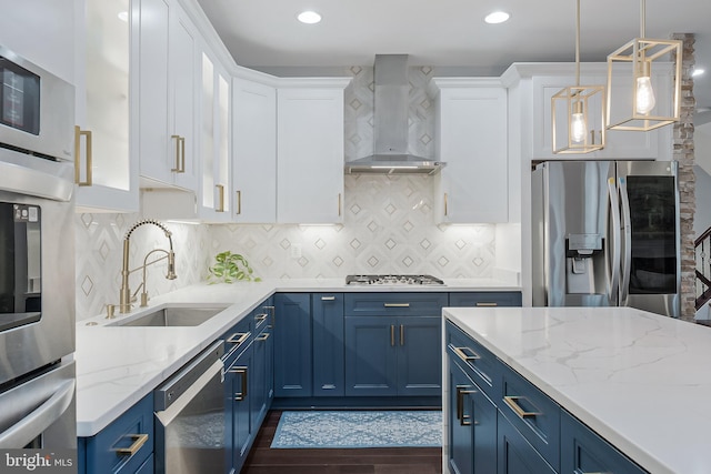19599 Aspendale Sq, Ashburn, VA 20147 - kitchen featuring appliances with stainless steel finishes, wall chimney range hood, blue cabinetry, a sink, and white cabinets