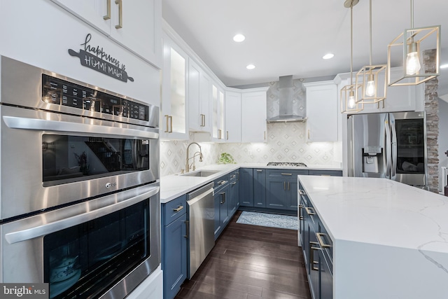 19599 Aspendale Sq, Ashburn, VA 20147 - kitchen featuring stainless steel appliances, wall chimney range hood, blue cabinets, a sink, and dark wood-type flooring