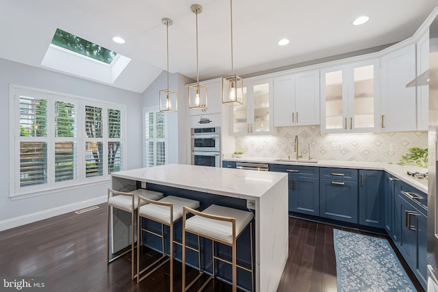 19599 Aspendale Sq, Ashburn, VA 20147 - kitchen with a skylight, a sink, blue cabinets, dark wood finished floors, and stainless steel double oven