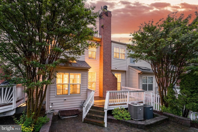 19599 Aspendale Sq, Ashburn, VA 20147 - rear view of house with a wooden deck, a chimney, and central AC