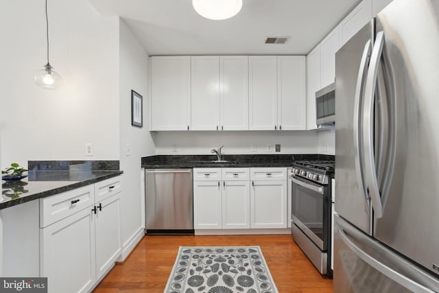 2120 Vermont Ave NW Unit 309, Washington, DC 20001 - kitchen with stainless steel appliances, white cabinetry, light wood-style floors, dark stone counters, and pendant lighting