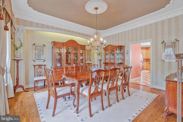 dining room with wallpapered walls, a notable chandelier, light wood-type flooring, baseboards, and ornamental molding