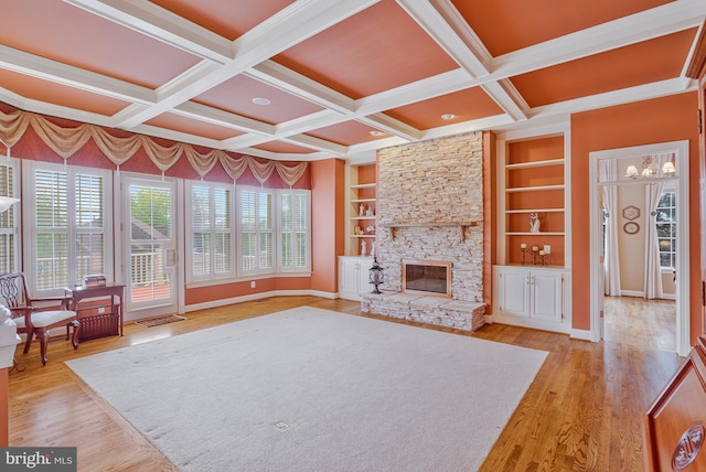 living room with wood finished floors, a notable chandelier, coffered ceiling, baseboards, and a stone fireplace