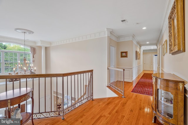 hall featuring wood finished floors, a chandelier, an upstairs landing, and ornamental molding