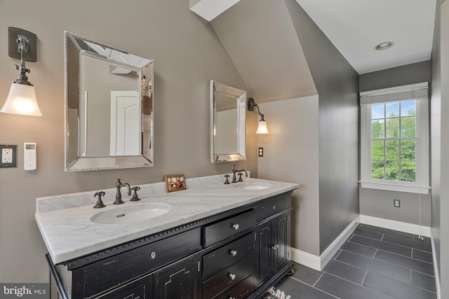 bathroom with double vanity, vaulted ceiling, baseboards, and a sink