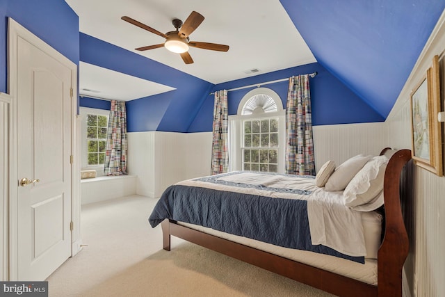 bedroom with carpet flooring, a ceiling fan, a wainscoted wall, visible vents, and lofted ceiling