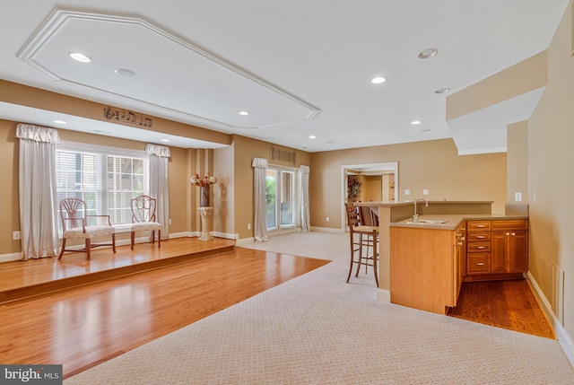 kitchen with a sink, wood finished floors, visible vents, a kitchen bar, and baseboards