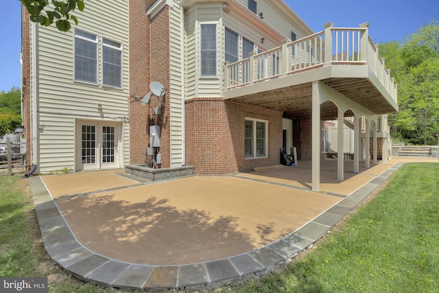 back of house with brick siding, a patio area, french doors, and a wooden deck