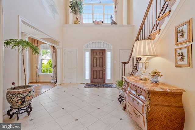 entrance foyer featuring a towering ceiling, stairs, and light tile patterned flooring