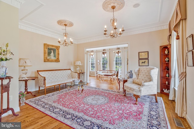living area featuring an inviting chandelier, french doors, wood finished floors, visible vents, and ornamental molding