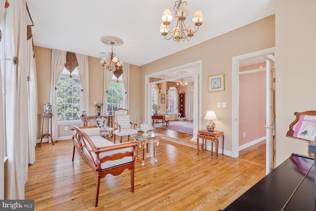 living area with a chandelier, baseboards, and light wood-style floors