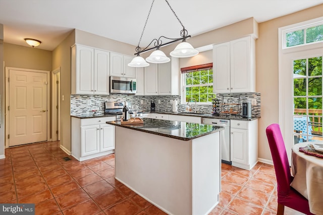 kitchen with stainless steel appliances, a sink, white cabinetry, and backsplash