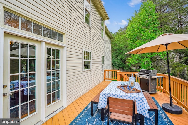 wooden terrace with outdoor dining area and a grill