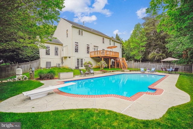 view of pool with stairs, a wooden deck, a patio area, and a diving board