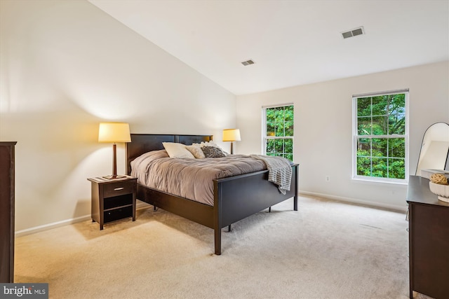 bedroom with light colored carpet, baseboards, and lofted ceiling
