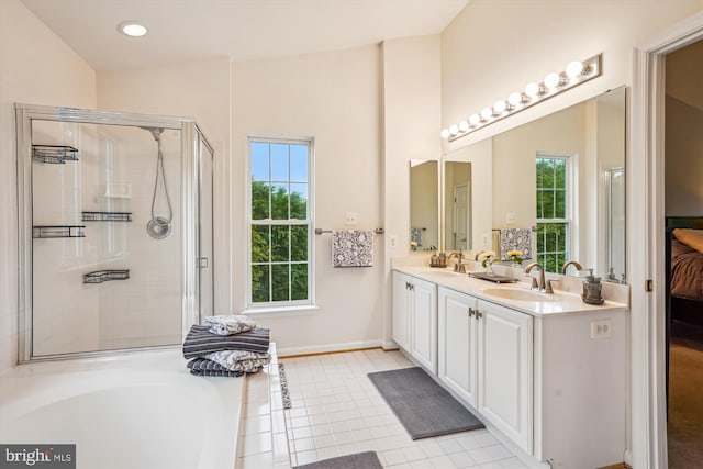 ensuite bathroom with a stall shower, double vanity, tile patterned flooring, a bathtub, and baseboards