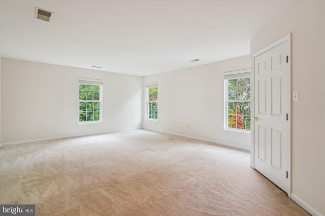 empty room featuring plenty of natural light, light carpet, and baseboards