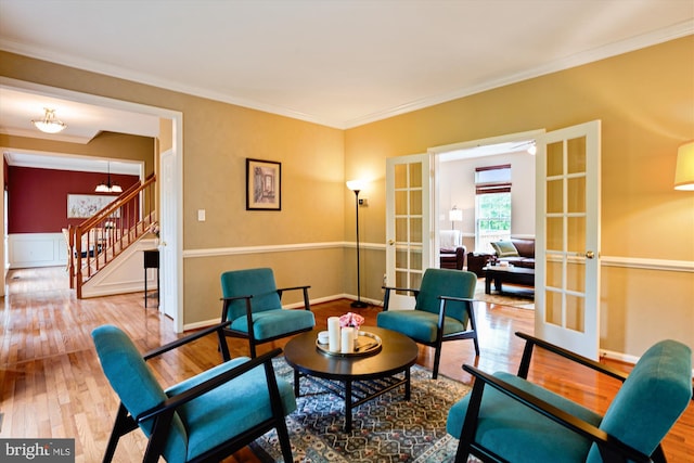 sitting room with french doors, stairway, wood finished floors, crown molding, and a chandelier