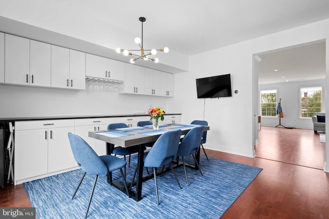 dining space with a chandelier, wood finished floors, and baseboards