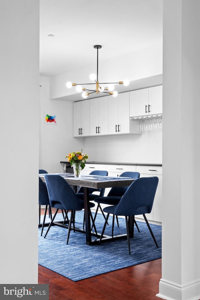 dining space with dark wood finished floors and a chandelier