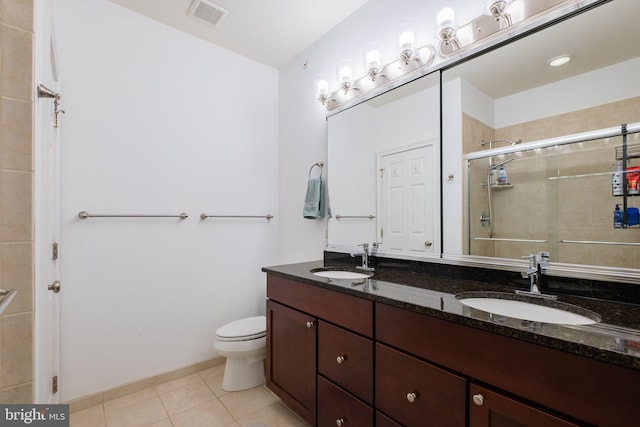 full bathroom featuring a stall shower, tile patterned floors, double vanity, and toilet