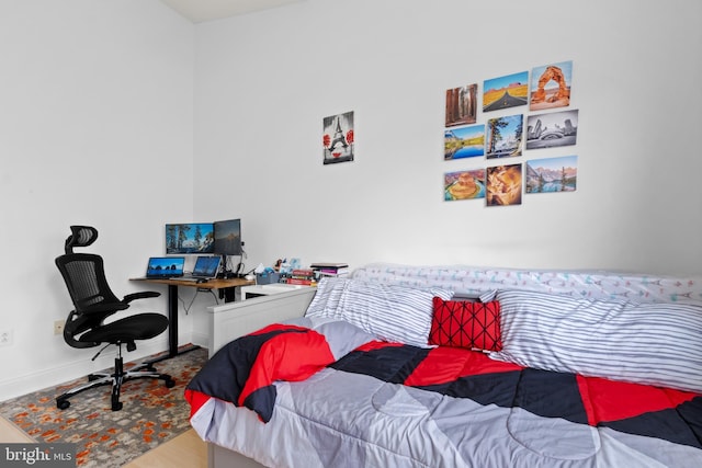 bedroom with wood finished floors, baseboards, and an office area