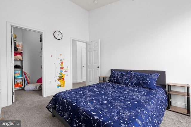 carpeted bedroom with baseboards and a high ceiling