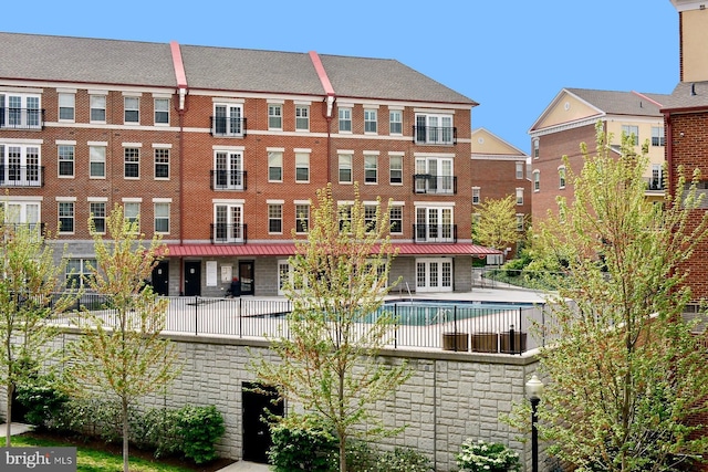 view of building exterior with a community pool and fence