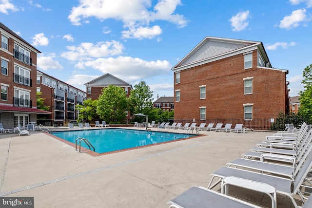 community pool with a patio area and fence