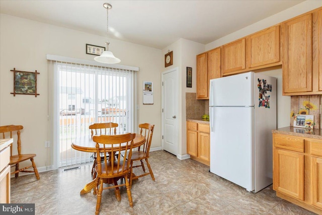 kitchen with freestanding refrigerator, visible vents, pendant lighting, backsplash, and baseboards