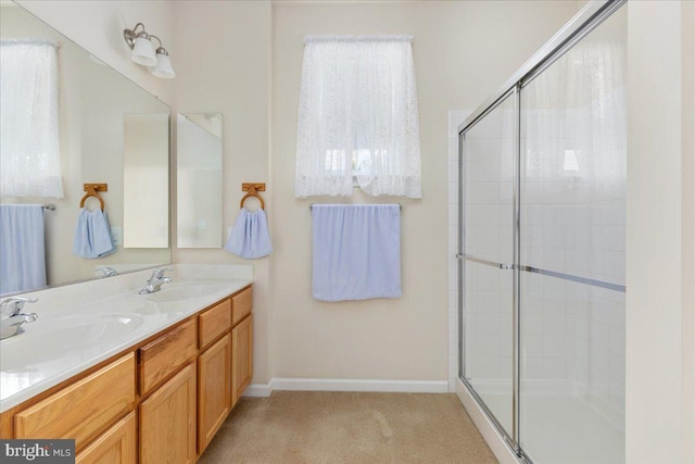 full bath with double vanity, baseboards, a tile shower, and a sink