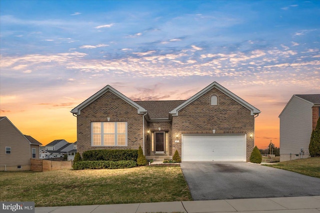 single story home featuring a yard, aphalt driveway, a garage, and brick siding
