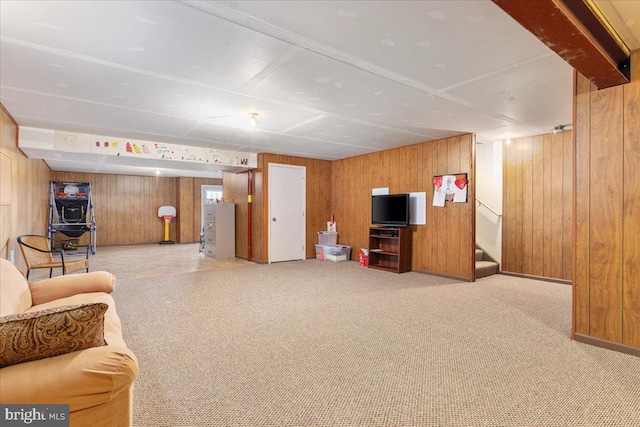 living area with carpet flooring, stairway, and wood walls