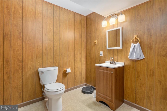 bathroom featuring vanity, toilet, baseboards, and wood walls