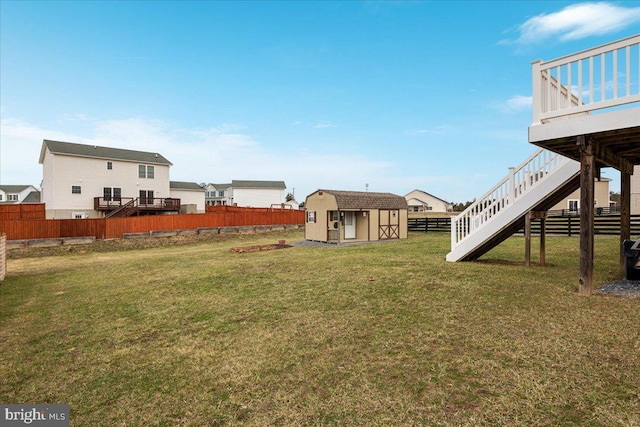 view of yard with an outdoor structure, a storage shed, a deck, stairway, and a fenced backyard