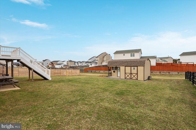 view of yard featuring an outdoor structure, a residential view, a fenced backyard, and a storage unit