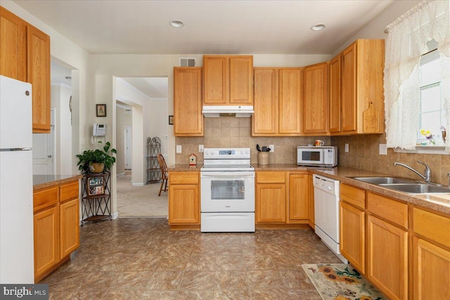 kitchen with under cabinet range hood, white appliances, visible vents, a sink, and decorative backsplash
