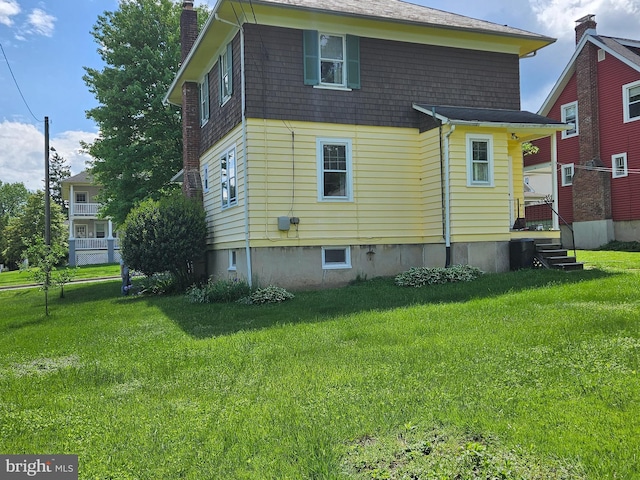 rear view of property featuring a chimney and a lawn