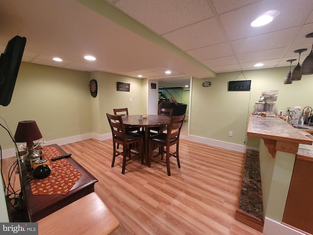 dining space featuring a drop ceiling, recessed lighting, baseboards, and light wood-style floors