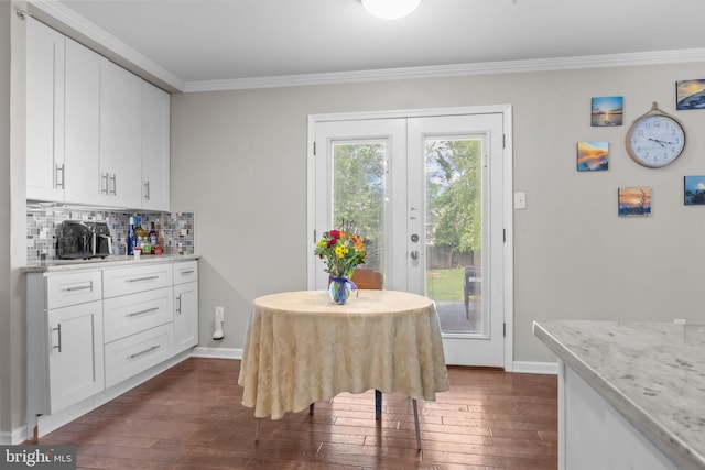 dining space with ornamental molding, dark wood finished floors, and baseboards