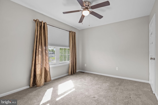 carpeted empty room featuring baseboards and ceiling fan