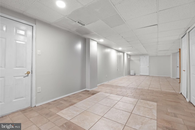 finished below grade area with baseboards, recessed lighting, a drop ceiling, and light tile patterned flooring