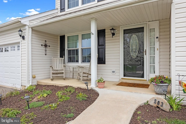 view of exterior entry featuring covered porch and a garage