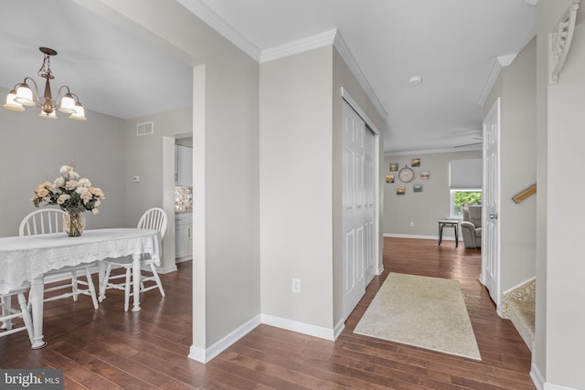 hall featuring hardwood / wood-style floors, a chandelier, ornamental molding, and baseboards