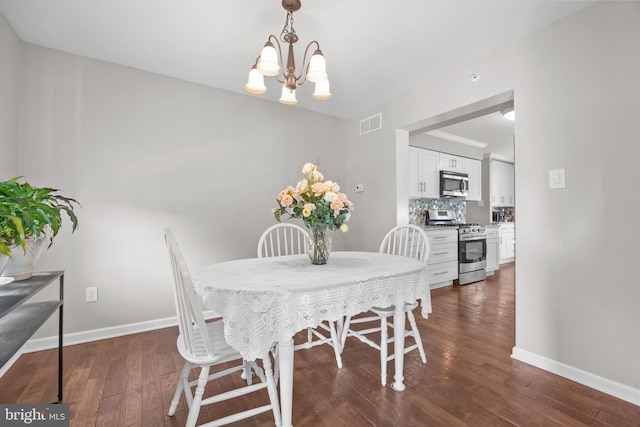 dining space featuring dark wood finished floors, a chandelier, and baseboards