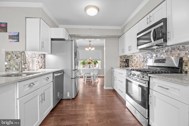 kitchen featuring stainless steel appliances, a sink, a chandelier, ornamental molding, and dark wood finished floors