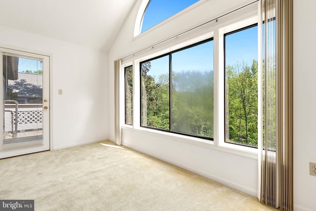 carpeted empty room with healthy amount of natural light, baseboards, and lofted ceiling