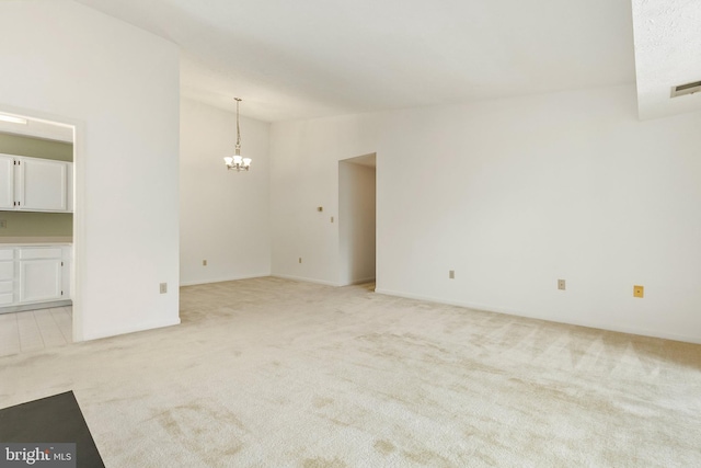unfurnished room featuring light colored carpet and a chandelier