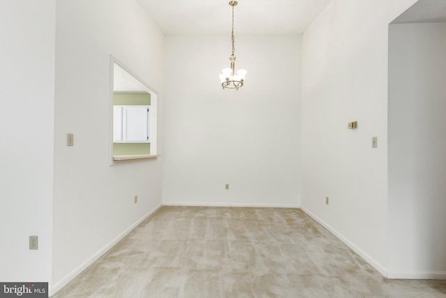carpeted spare room featuring a chandelier and baseboards
