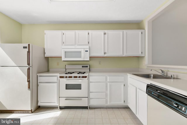 kitchen with white appliances, a sink, white cabinetry, and light countertops
